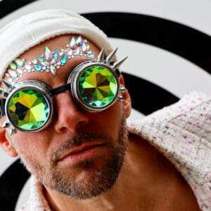 Man wearing colorful, kaleidoscopic glasses and a white headscarf.