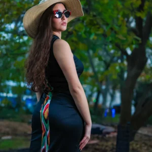 Woman in black dress and sunhat posing outdoors.