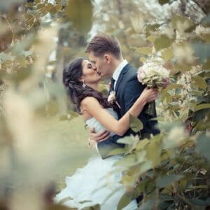 A couple embraces in a dreamy, floral outdoor setting.